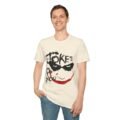 A man wearing a cream-colored Dark Joker Smile Graphic T-Shirt featuring a sinister black and red hand-painted Joker face aesthetic.