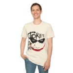 A man wearing a cream-colored Dark Joker Smile Graphic T-Shirt featuring a sinister black and red hand-painted Joker face aesthetic.