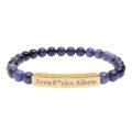 A premium Engraved Natural Stone Bracelet featuring deep purple jasper beads and a gold stainless steel bar engraved with the bold statement "Zero F*cks Given."