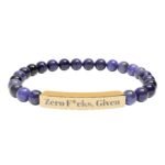 A premium Engraved Natural Stone Bracelet featuring deep purple jasper beads and a gold stainless steel bar engraved with the bold statement "Zero F*cks Given."
